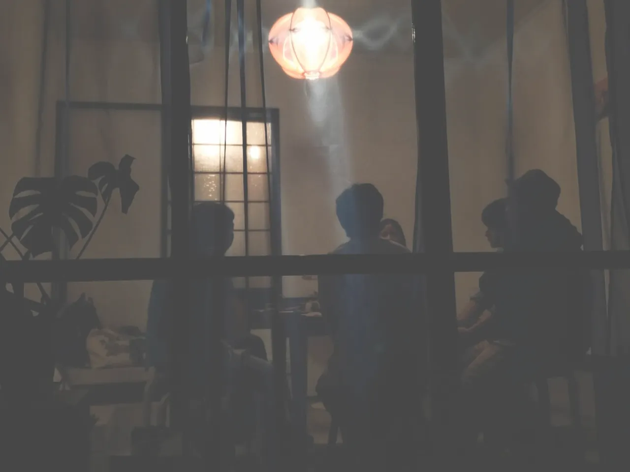 夜のOKAYU HOTELでテーブルを囲んで語らう参加者たちのシルエット